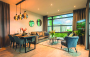 Moderne woonkamer in Villa Maritiem lodge met eettafel, knusse zithoek en grote ramen met uitzicht.