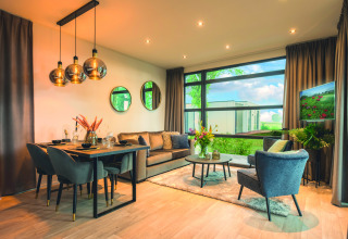Soggiorno moderno nella Villa Maritiem lodge con tavolo da pranzo, area relax e ampie finestre.