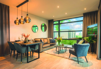Moderne woonkamer in Villa Maritiem lodge met eettafel, knusse zithoek en grote ramen met uitzicht.