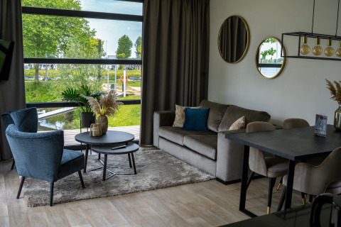 Sala moderna en la Villa Maritiem de MarinaPark Bad Nederrijn, Países Bajos, con grandes ventanas y vista al agua.
