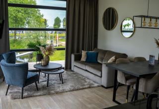 Sala moderna en la Villa Maritiem de MarinaPark Bad Nederrijn, Países Bajos, con grandes ventanas y vista al agua.