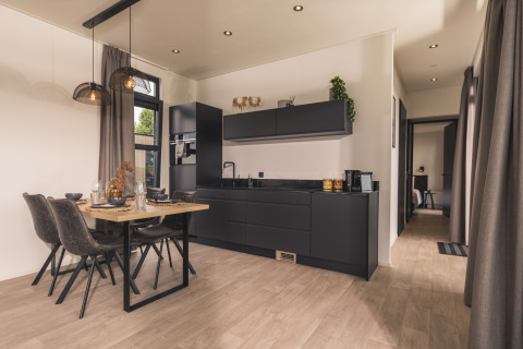 Cucina nera moderna e zona pranzo elegante nella Villa Maritiem, MarinaPark Bad Nederrijn, Paesi Bassi, ben arredata.