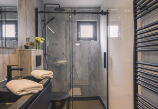 Baño moderno en la Villa Maritiem en MarinaPark Bad Nederrijn, Países Bajos, con ducha de cristal.