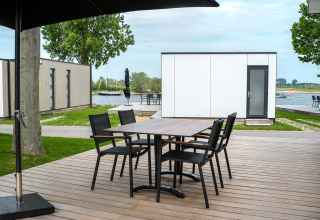 Terraza exterior con mesa y sillas en Villa Maritiem, MarinaPark Bad Nederrijn, Países Bajos, junto al agua.