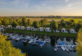 Vista de los lodges Villa Maritiem en MarinaPark Bad Nederrijn, Países Bajos, barcos en el puerto y campo.