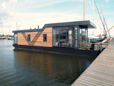Moderne woonboot aangemeerd bij Waterlodge 4, Zuiderzee, Nederland, met houten panelen en grote ramen.