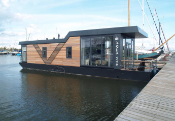 Modernes Hausboot am Steg bei Waterlodge 4 in Zuiderzee, Niederlande, mit Holz- und Glasfront.