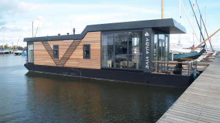 Modernes Hausboot am Steg bei Waterlodge 4 in Zuiderzee, Niederlande, mit Holz- und Glasfront.
