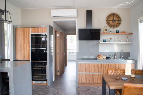 Moderne Küche in der Waterlodge 4 am Zuiderzee, Niederlande, mit Holzmöbeln, Esstisch und offenem Regal.