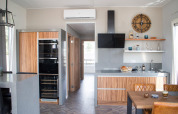 Moderne køkken interiør i Waterlodge 4 ved Zuiderzee, Holland, med træfinish, åbne hylder og spiseplads.