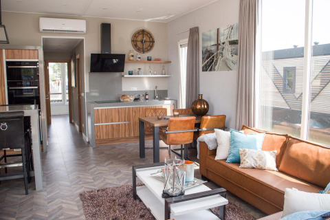 Moderne leef- en keukenruimte in Waterlodge 4 te Zuiderzee, Nederland, met grote ramen en knusse sfeer.