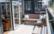 Udendørs terrasse med siddepladser og puder på Waterlodge 4 ved Zuiderzee i Holland, udsigt til kanalen.