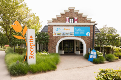 Ingang van de receptie bij Waterlodge 4 in EuroParcs Zuiderzee, Nederland, omgeven door planten.