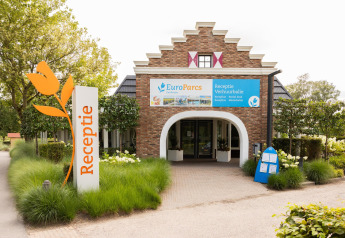 Entrance to the reception of Waterlodge 4 at EuroParcs Zuiderzee in the Netherlands, with lush greenery.