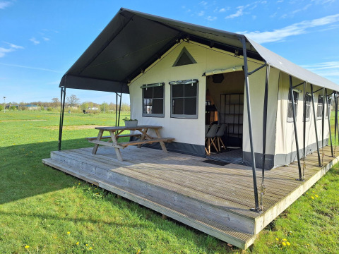 Tienda safari glamping en CharmeCamping De Regge-Vallei, Países Bajos, con terraza y banco de madera.