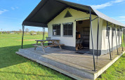 Tente safari glamping au CharmeCamping De Regge-Vallei aux Pays-Bas, avec terrasse en bois et banc extérieur.