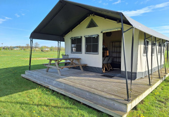 Safari glamping tent at CharmeCamping De Regge-Vallei in the Netherlands with wooden deck and bench.