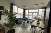 Living room at Waterlodge 6, Zuiderzee, Netherlands with blue sofa, dining table and harbor view outside.