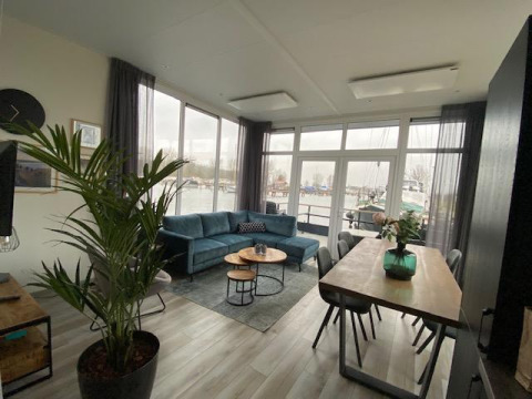 Living room at Waterlodge 6, Zuiderzee, Netherlands with blue sofa, dining table and harbor view outside.