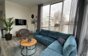 Stilfuld stue i Waterlodge 6 ved Zuiderzee, Nederlandene, med udsigt til vand og en moderne sofa.