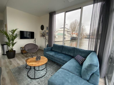 Stylish living room at Waterlodge 6 by Zuiderzee, Netherlands, with a large blue sofa and water views.