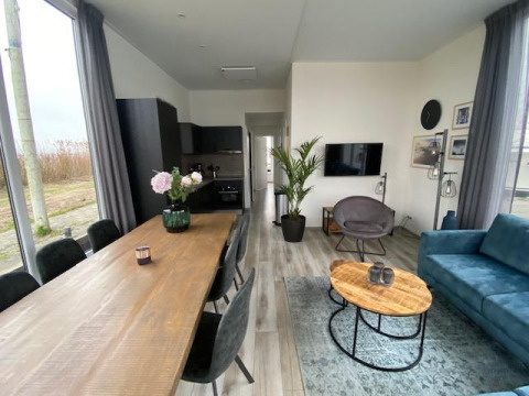 Salon et salle à manger modernes dans la Waterlodge 6 à Zuiderzee, Pays-Bas, avec de grandes fenêtres.