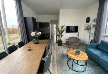 Moderne leefruimte en keuken in Waterlodge 6 aan het Zuiderzee, Nederland, met grote ramen en sfeervolle inrichting.