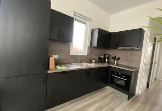Moderne sort køkken i Waterlodge 6 ved Zuiderzee, Holland, med vindue, ovn og kaffeudstyr.
