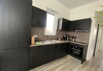 Moderne zwarte keuken in Waterlodge 6 aan Zuiderzee, Nederland, met oven, raam en koffiezetapparaat.