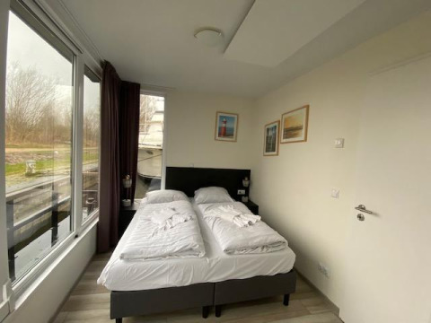 Dormitorio en Waterlodge 6 en Zuiderzee, Países Bajos, con dos camas individuales y vista al agua.