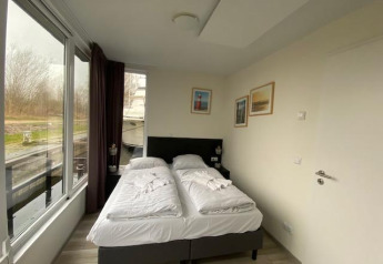 Soveværelse i Waterlodge 6 ved Zuiderzee, Holland med to enkeltsenge, vindue og landskabsudsigt.