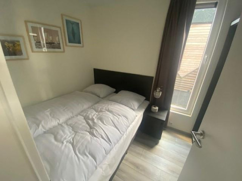 Schlafzimmer mit Doppelbett, Nachttisch und Fenster in Waterlodge 6 am Zuiderzee, Niederlande, modern eingerichtet.