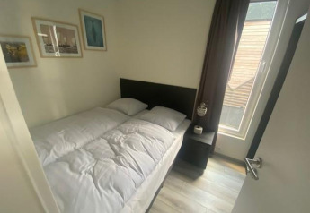 Slaapkamer met dubbel bed, nachtkastje en raam in Waterlodge 6 bij Zuiderzee, Nederland, gezellig ingericht.