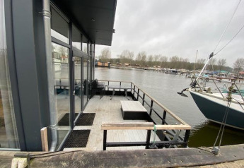 Terras van Waterlodge 6 aan de Zuiderzee in Nederland met zicht op aanlegsteiger en plezierboten.