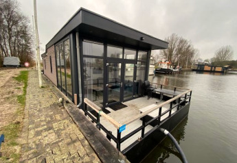 Moderne vandhytte ved Zuiderzee i Holland, placeret direkte på vandet med terrasse og glasfacader.