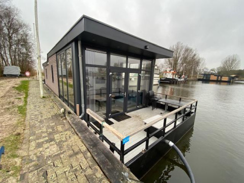 Modern water lodge at Zuiderzee in the Netherlands, situated on the water with glass walls and deck.