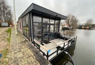 Modern water lodge at Zuiderzee in the Netherlands, situated on the water with glass walls and deck.