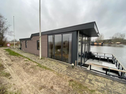 Vue extérieure de la Waterlodge 6 à Zuiderzee aux Pays-Bas, située au bord de l'eau sous un ciel gris.