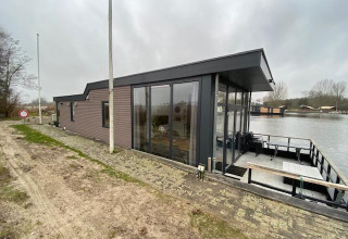 Vista exterior de Waterlodge 6 en Zuiderzee, Países Bajos, junto al agua y bajo un cielo nublado y gris.