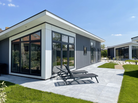 Moderne Premium Lodge bij Kompas Camping - Westende in België met zonnig terras en ligstoelen buiten.