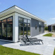 Lodge moderno Premium en Kompas Camping - Westende, Bélgica, con terraza soleada y sillas reclinables.
