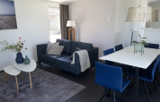 Salón moderno y comedor en la Premium Lodge de Kompas Camping - Westende, Bélgica, con sillas azules.