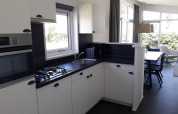 Moderne keuken met witte kasten en zwarte werkblad in Premium Lodge bij Kompas Camping Westende, België.