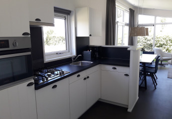 Cucina moderna con mobili bianchi e piano nero al Premium Lodge di Kompas Camping Westende in Belgio.