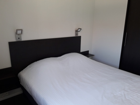 Moderne slaapkamer in Premium Lodge bij Kompas Camping - Westende, België, met tweepersoonsbed en eenvoudige inrichting.