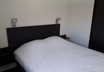 Moderne slaapkamer in Premium Lodge van Kompas Camping - Westende, België, met tweepersoonsbed en strakke stijl.