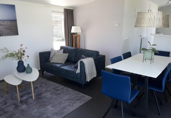 Soggiorno e sala da pranzo moderni nella Premium Lodge di Kompas Camping - Westende, Belgio, con divano blu.