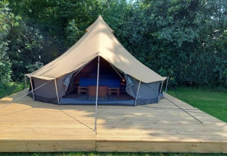 Tenda belltent di lusso su piattaforma di legno a CharmeCamping De Regge-Vallei, Paesi Bassi, tra alberi verdi.