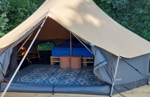 Interior de una tienda belltent de lujo con cama y muebles en CharmeCamping De Regge-Vallei, Países Bajos.