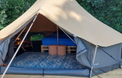 Interieur van een luxe belltent met bed en meubels bij CharmeCamping De Regge-Vallei, Nederland.